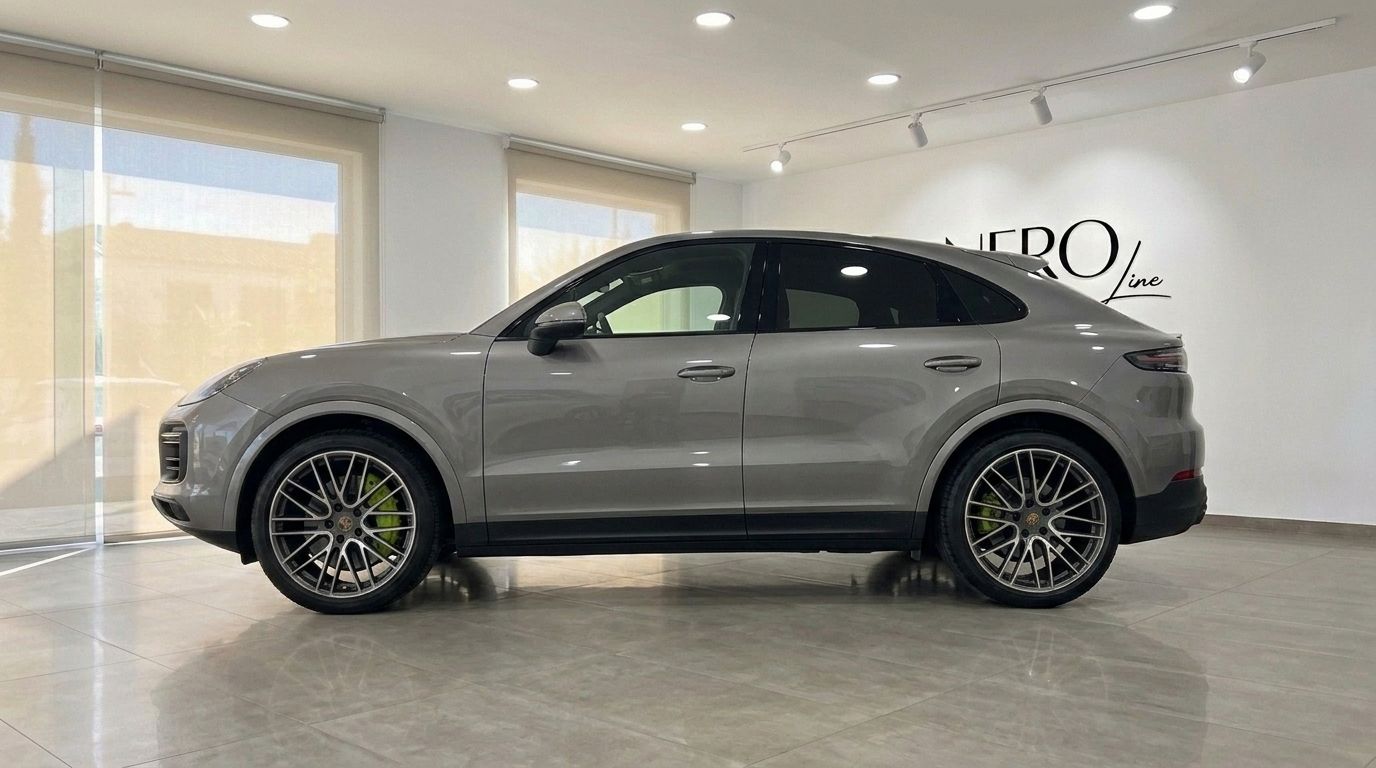 The 2024 Porsche Cayenne in gloss metallic Quarzite Grey Metallic, showcasing its sleek side profile inside a showroom in Mallorca.