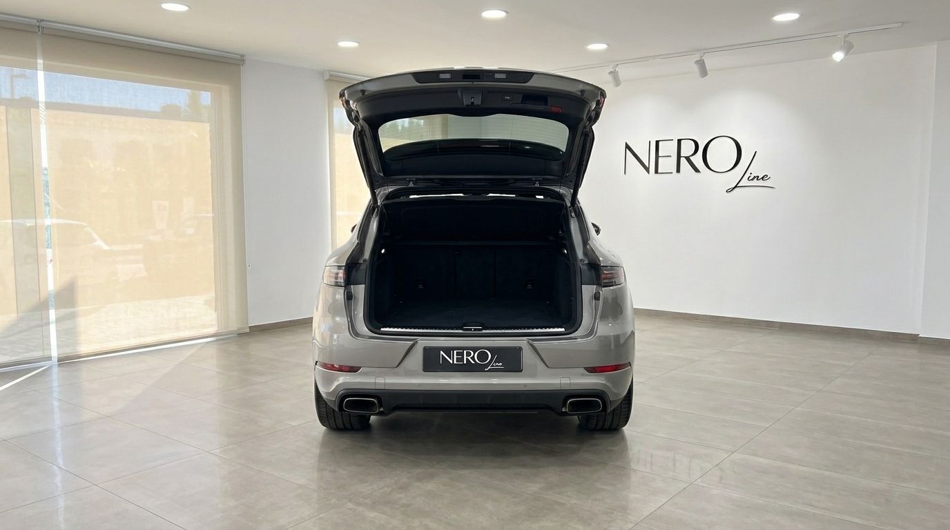 The rear view of a grey Porsche Cayenne with its trunk open, showcasing its spacious cargo area in Mallorca.