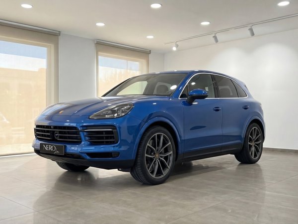 Porsche Cayenne — Blue SUV in Mallorca Showroom The blue 2024 Porsche Cayenne is showcased in a front three-quarter view inside a bright showroom in Mallorca.