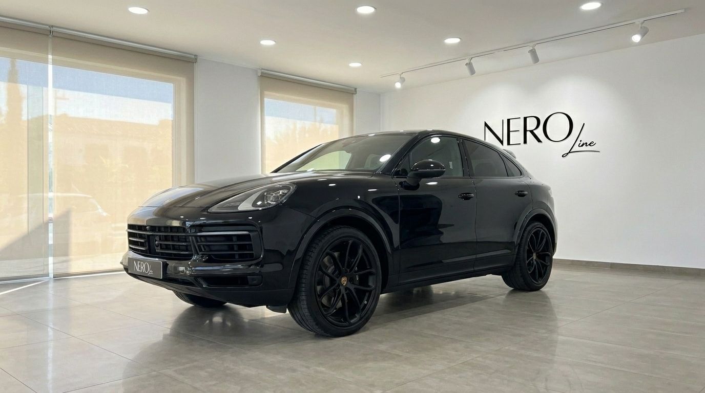 A sleek black Porsche Cayenne is displayed in a modern showroom with large windows, Alicante.