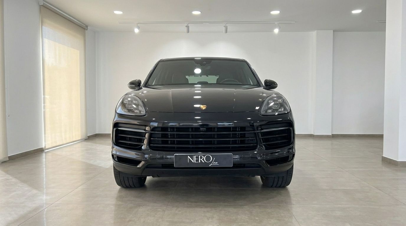 The black Porsche Cayenne is prominently displayed from a front view in a bright showroom in Alicante.