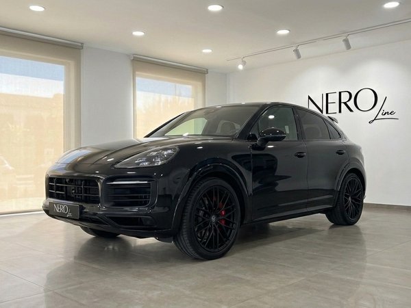 Porsche Cayenne GTS — Showroom in Alicante A sleek gloss black 2026 Porsche Cayenne GTS is prominently displayed from a front three-quarter view in a modern showroom in Alicante.