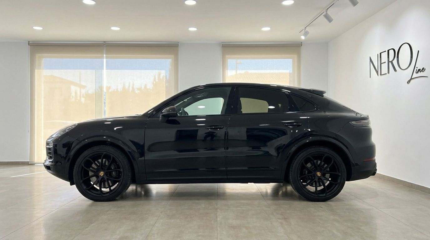 The black 2020 Porsche Cayenne is shown from its left side profile, parked in a bright showroom in Alicante.