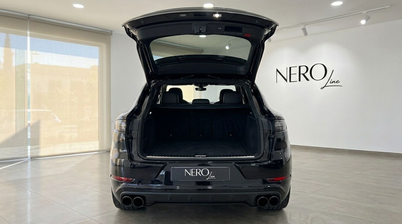 The black Porsche Cayenne is shown from the rear with its boot open, revealing the spacious cargo area in Alicante.