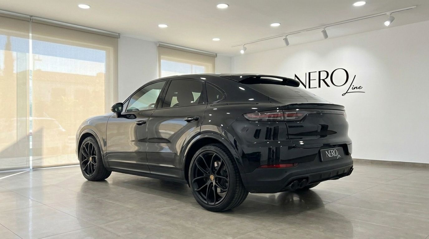The sleek black Porsche Cayenne from 2020 is showcased from its rear three-quarter angle in a bright showroom in Alicante.