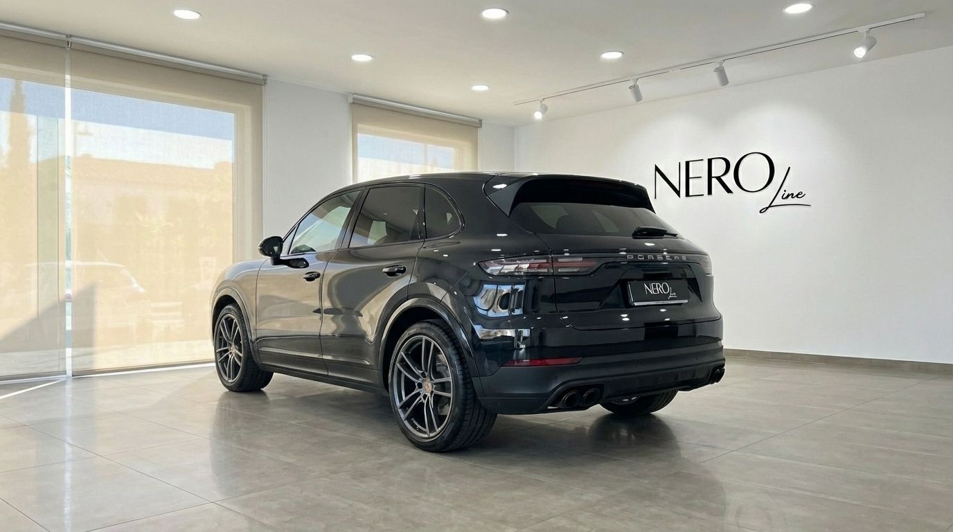 The black 2022 Porsche Cayenne is showcased from its sleek rear three-quarter angle in a bright Barcelona showroom.