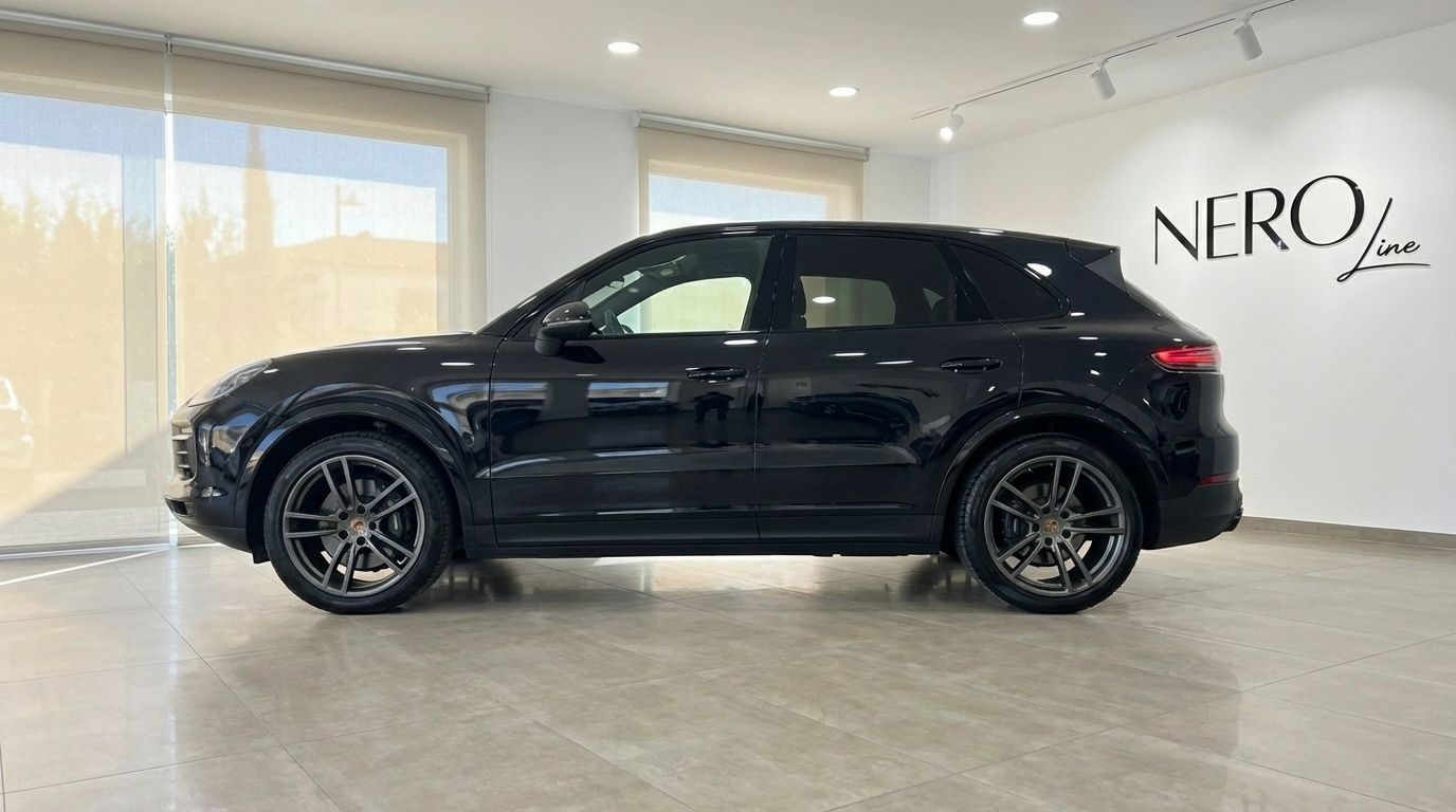 The black 2022 Porsche Cayenne is shown in a side profile view inside a bright showroom in Barcelona.