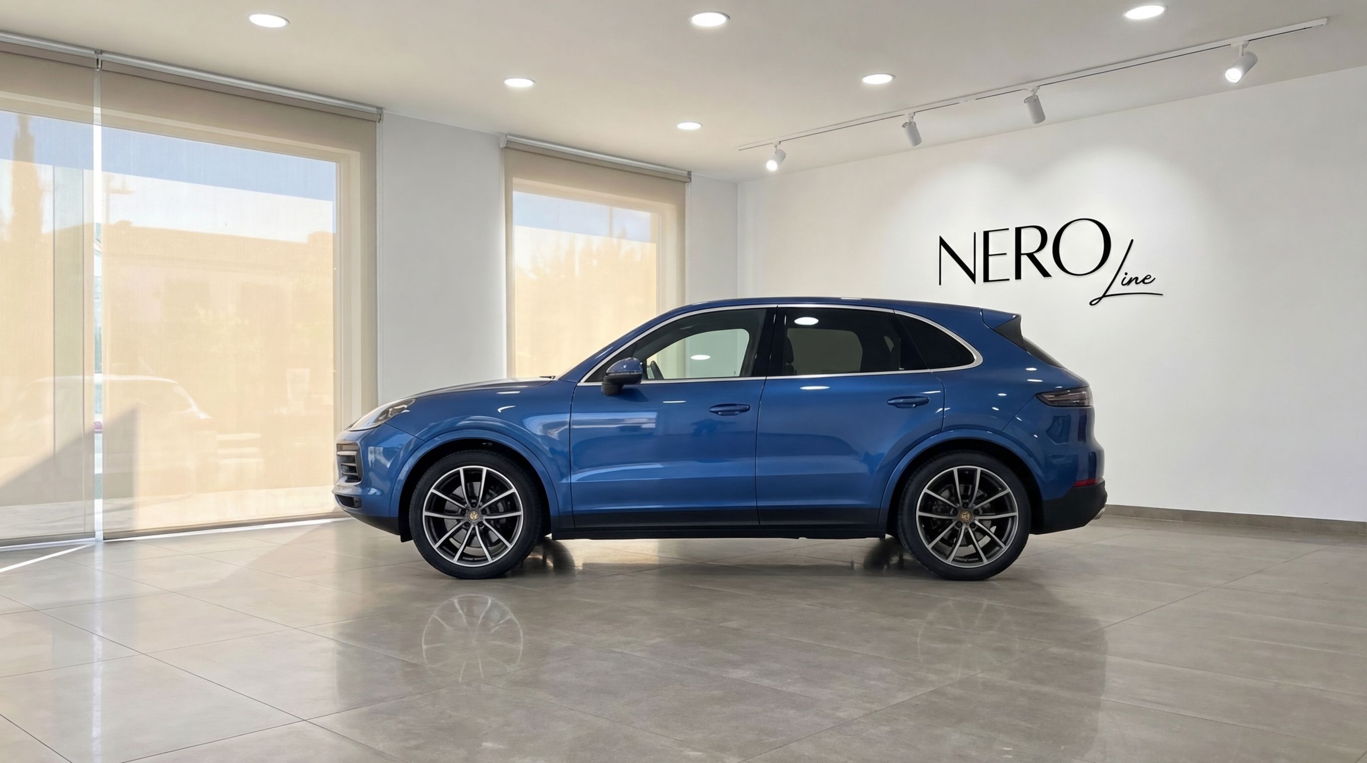 The blue Porsche Cayenne is showcased in a modern showroom with the Nero Line logo visible on the wall in Mallorca.