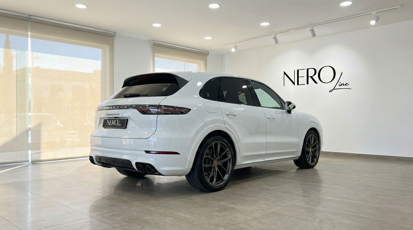 The white Porsche Cayenne Turbo GT is showcased from a rear three-quarter view inside a modern showroom in Valencia.