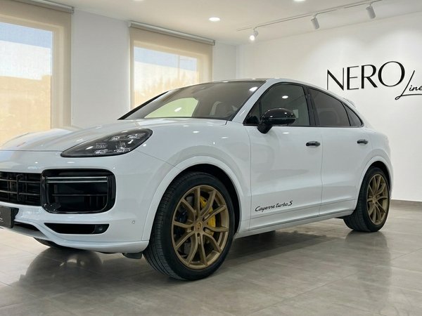 Porsche Cayenne Turbo S E-Hybrid — Showroom view The white Porsche Cayenne Turbo S E-Hybrid is displayed in a showroom in Alicante, showing its front three-quarter view with gold wheels.