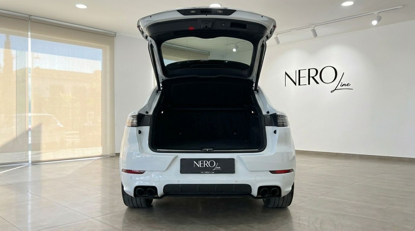 The white Porsche Cayenne Turbo S E-Hybrid is shown from the rear with its boot open, highlighting its spacious cargo area in Alicante.