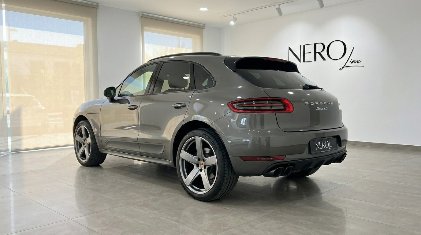 Porsche Macan 2.0 Turbo — Rear three-quarter view A gloss Volcano Grey Metallic Porsche Macan 2.0 Turbo is showcased from a rear three-quarter angle in a bright Alicante showroom.