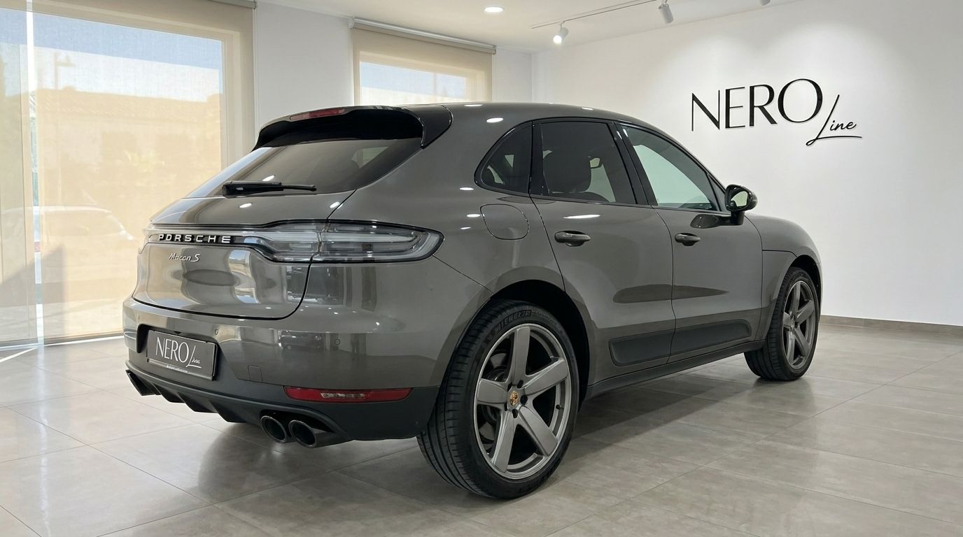 The gloss Volcano Grey Metallic Porsche Macan 2.0 Turbo, viewed from the rear three-quarter angle in a showroom in Alicante.