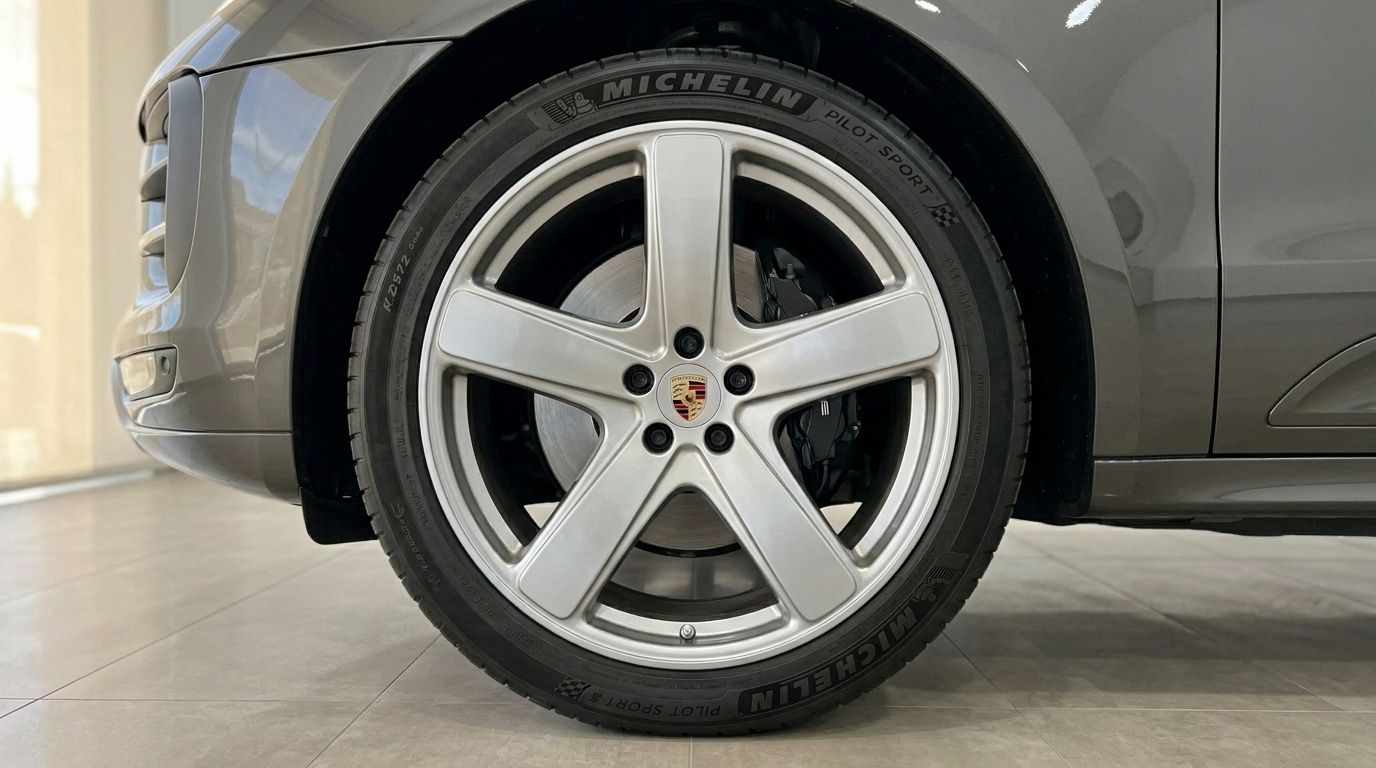 Close-up of the front wheel and silver five-spoke rim on a gloss Volcano Grey Metallic Porsche Macan 2.0 Turbo in Alicante.