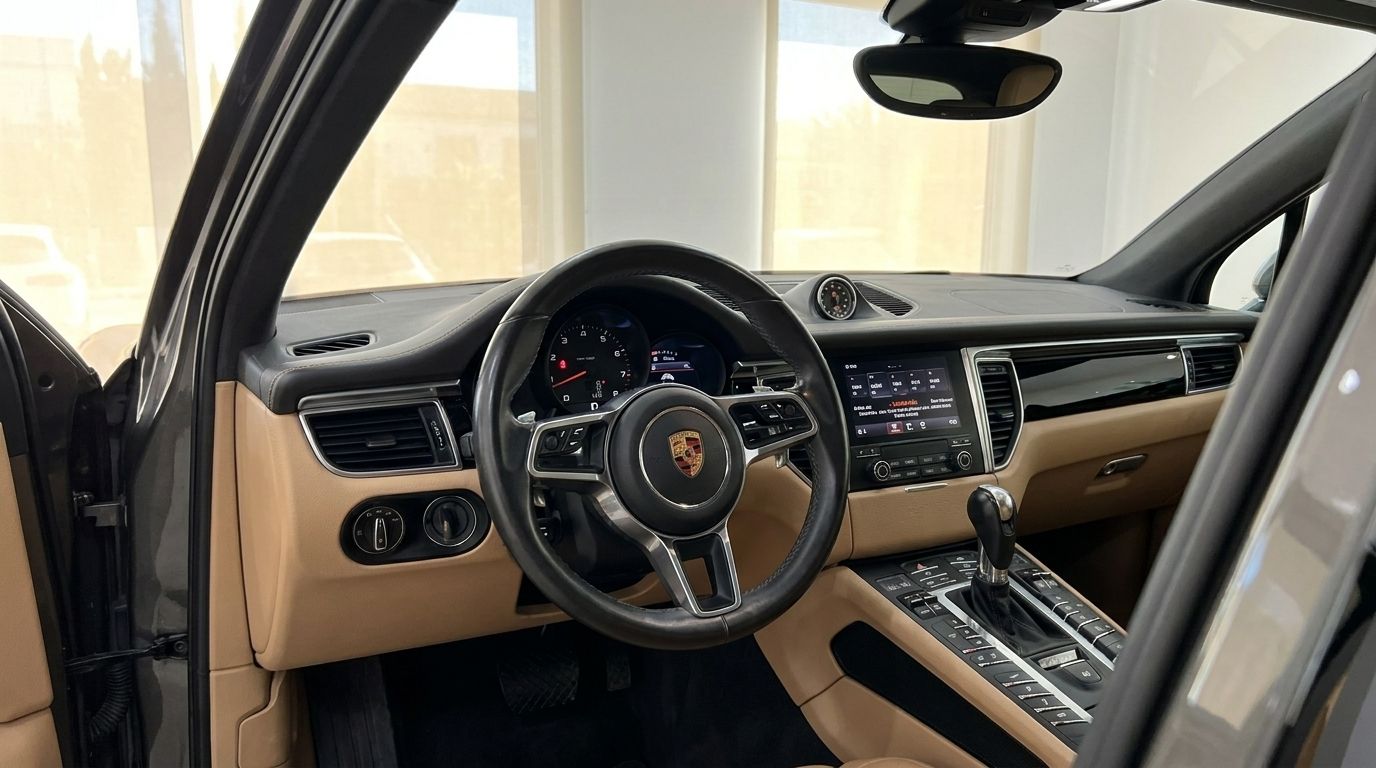 The luxurious interior of the Porsche Macan 2.0 Turbo in Alicante, featuring its steering wheel, dashboard, and infotainment system.