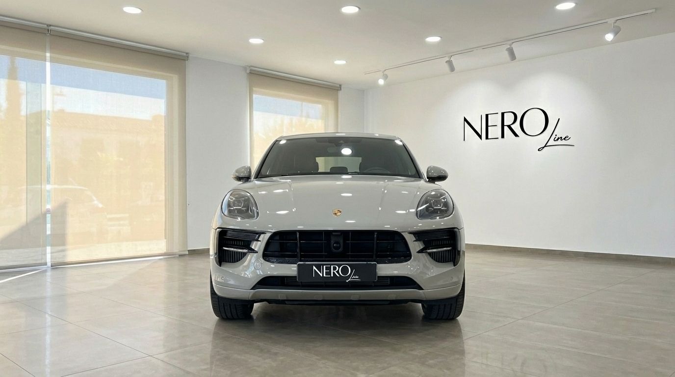 The light gray 2021 Porsche Macan S is showcased from the front view in a modern showroom in Alicante.