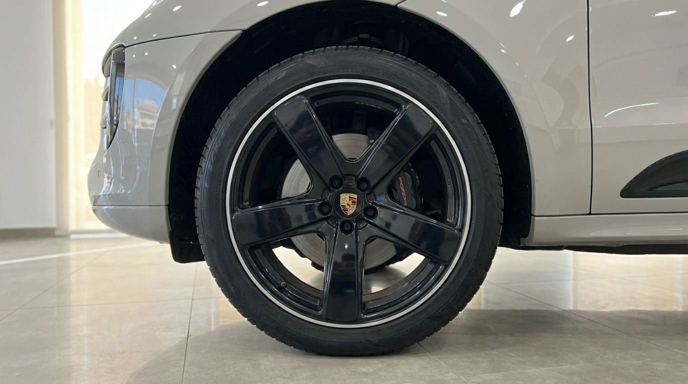 Close-up of the black front wheel with red brake calipers on a light gray Porsche Macan S in Alicante.