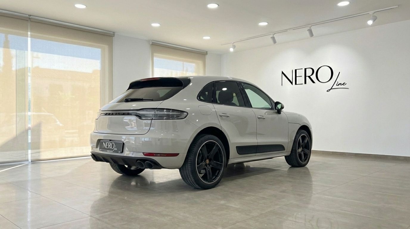 The light gray 2021 Porsche Macan S is showcased from a rear three-quarter angle in a bright showroom in Alicante.