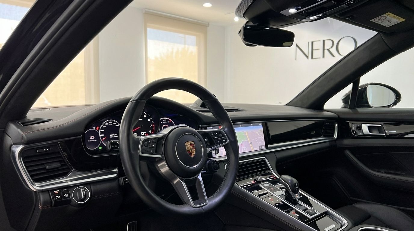 The luxurious black interior and cockpit of the Porsche Panamera GTS, featuring the steering wheel, dashboard, and central console, available for rent in Alicante.