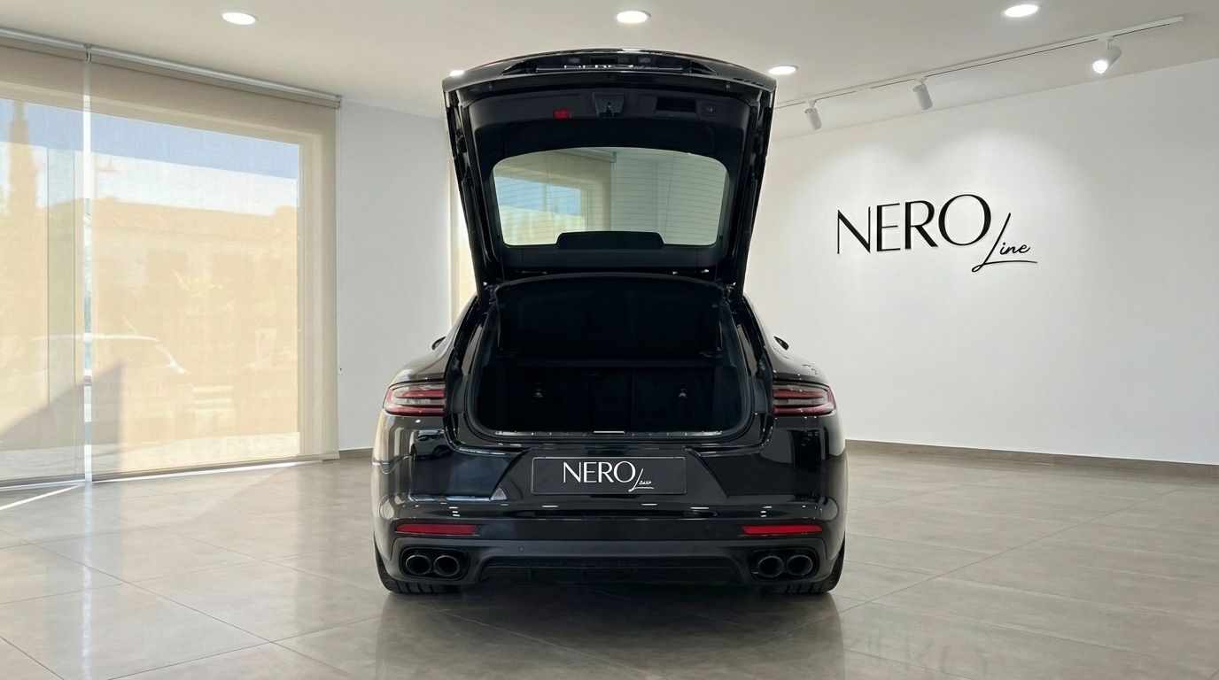 The black Porsche Panamera GTS is shown from the rear with its trunk open, parked in a showroom in Alicante.