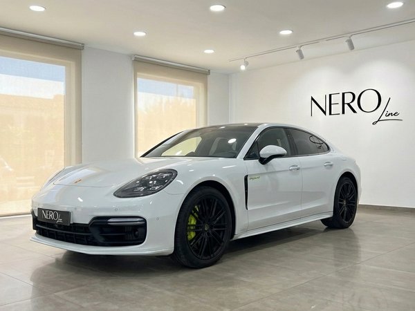 Porsche Panamera Turbo S Hybrid — Showroom Alicante The white Porsche Panamera Turbo S Hybrid is parked in a showroom in Alicante, showing its front three-quarter view.