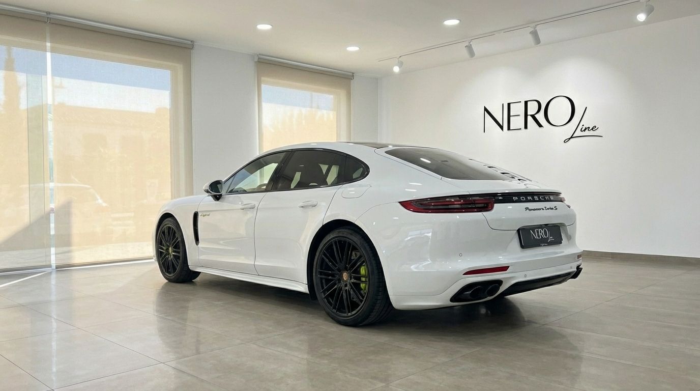 The white Porsche Panamera Turbo S Hybrid is parked in a showroom, viewed from the rear three-quarter angle in Alicante.