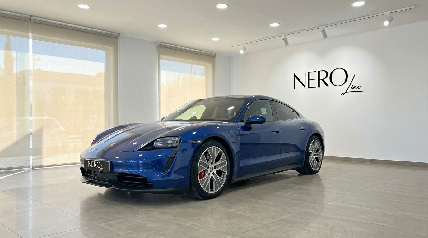 The blue Porsche Taycan 4S electric sedan is showcased in a modern showroom with large windows in Alicante.