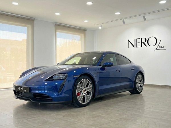 Porsche Taycan 4S — Luxury Electric Sedan in Alicante The blue Porsche Taycan 4S electric sedan is showcased in a modern showroom with large windows in Alicante.