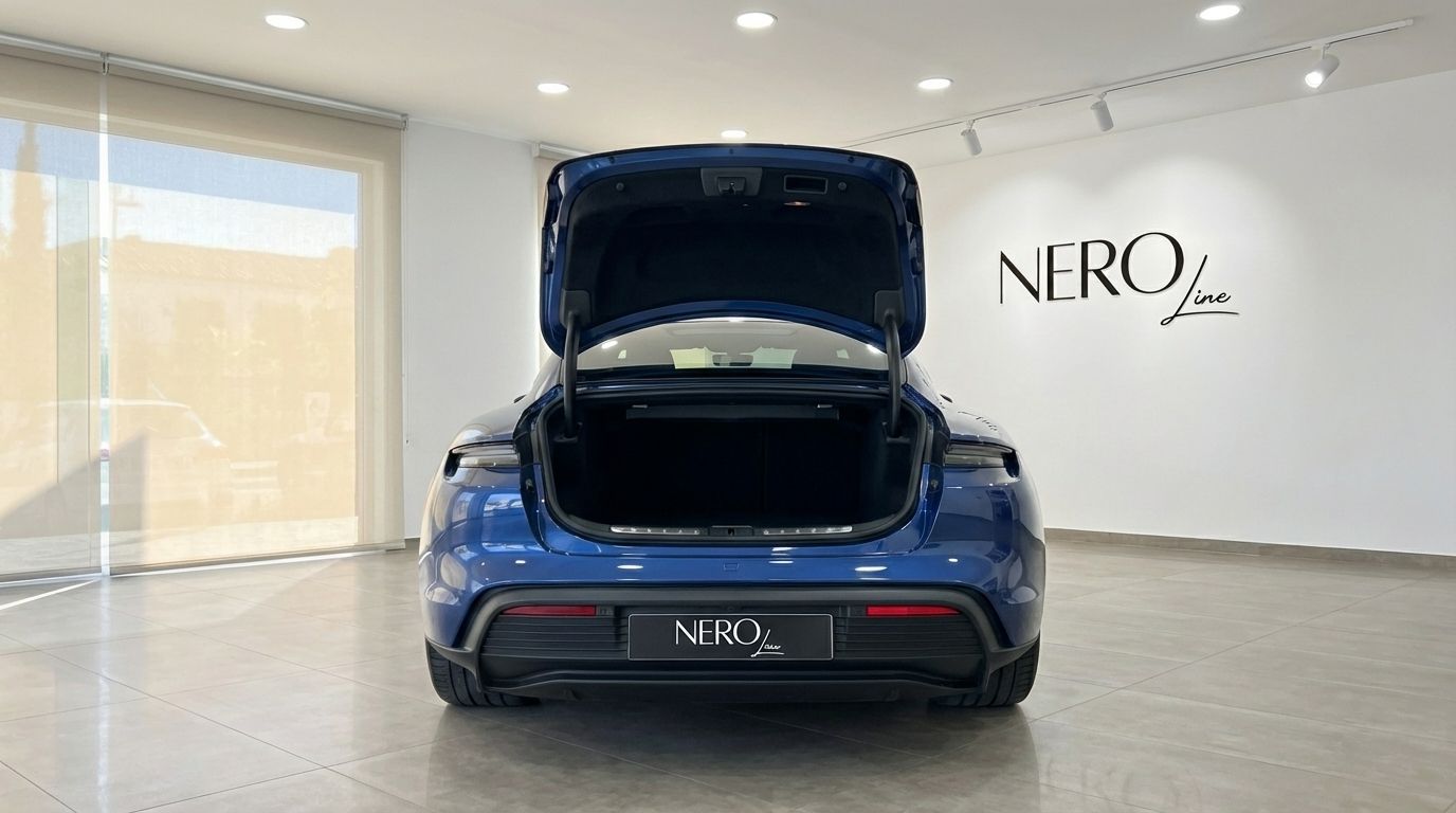 The blue 2022 Porsche Taycan 4S is shown from the rear with its trunk open, parked inside a showroom in Alicante.