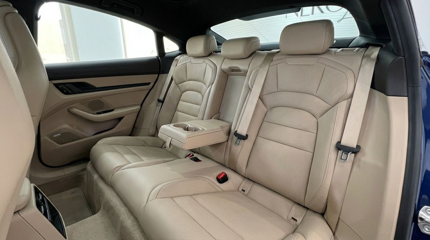 Porsche Taycan 4S rear interior in Alicante, featuring luxurious beige leather seats and a central armrest with cupholders.
