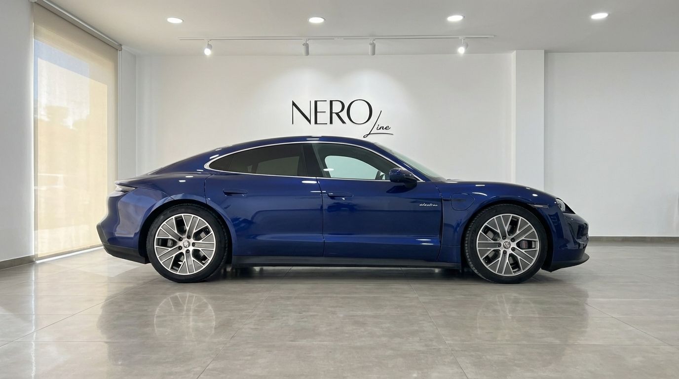 The blue Porsche Taycan 4S is showcased in a full side profile view, parked inside a modern showroom in Alicante.