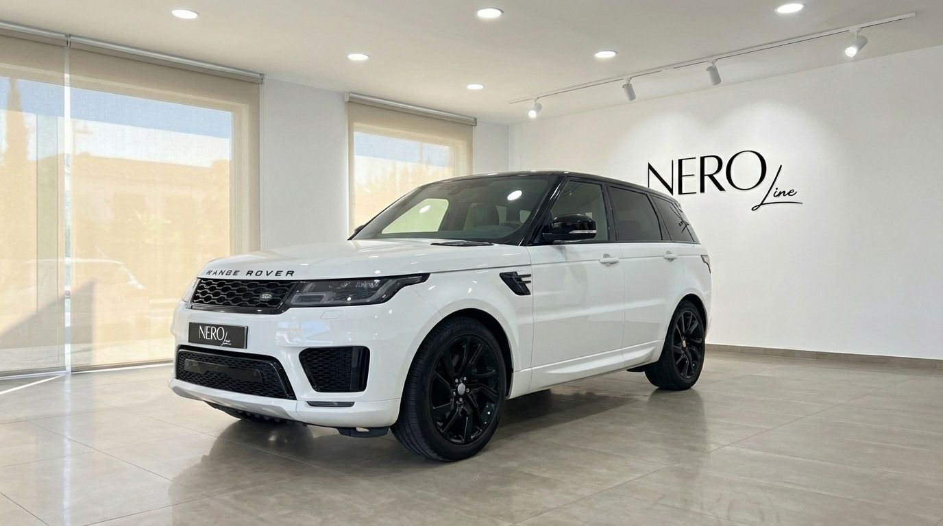 A white Range Rover Sport with a black roof and black wheels is parked in a showroom in Barcelona, seen from a front three-quarter angle.