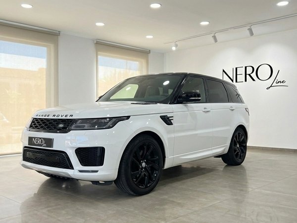 Range Rover Sport — Front three-quarter view A white Range Rover Sport with a black roof and black wheels is parked in a showroom in Barcelona, seen from a front three-quarter angle.