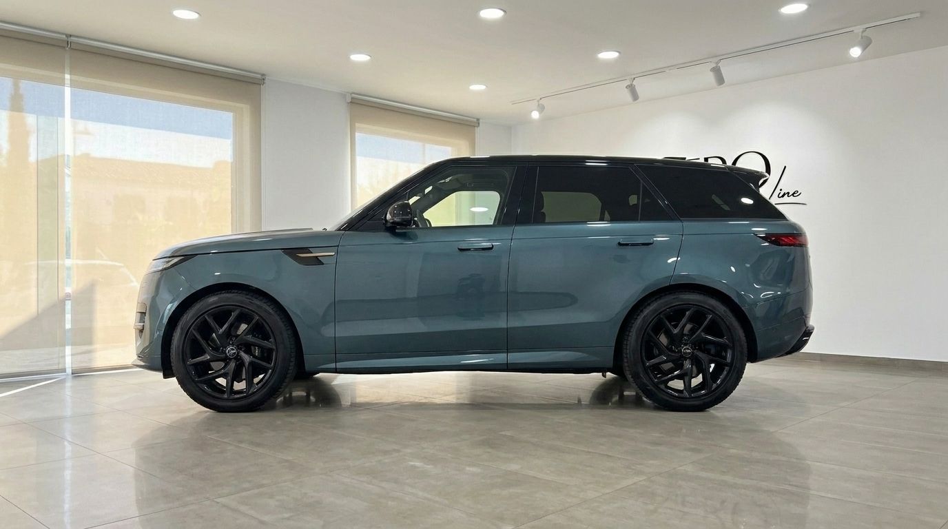 El Range Rover Sport 2023 en verde Giola metalizado se muestra de perfil, destacando su diseño elegante y llantas negras en un concesionario de Madrid.