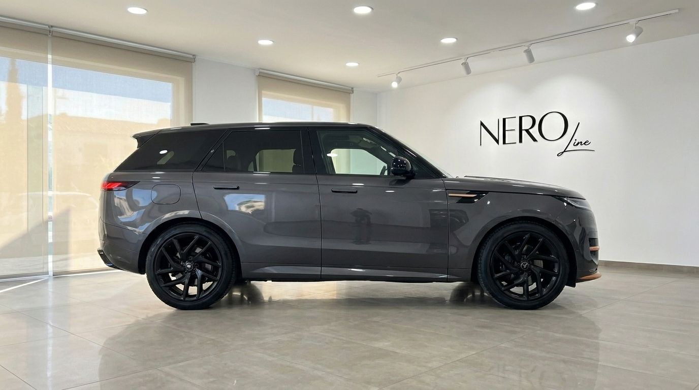 El Range Rover Sport 2023 en un elegante acabado gris, capturado de perfil lateral dentro de una sala de exposición en Madrid.