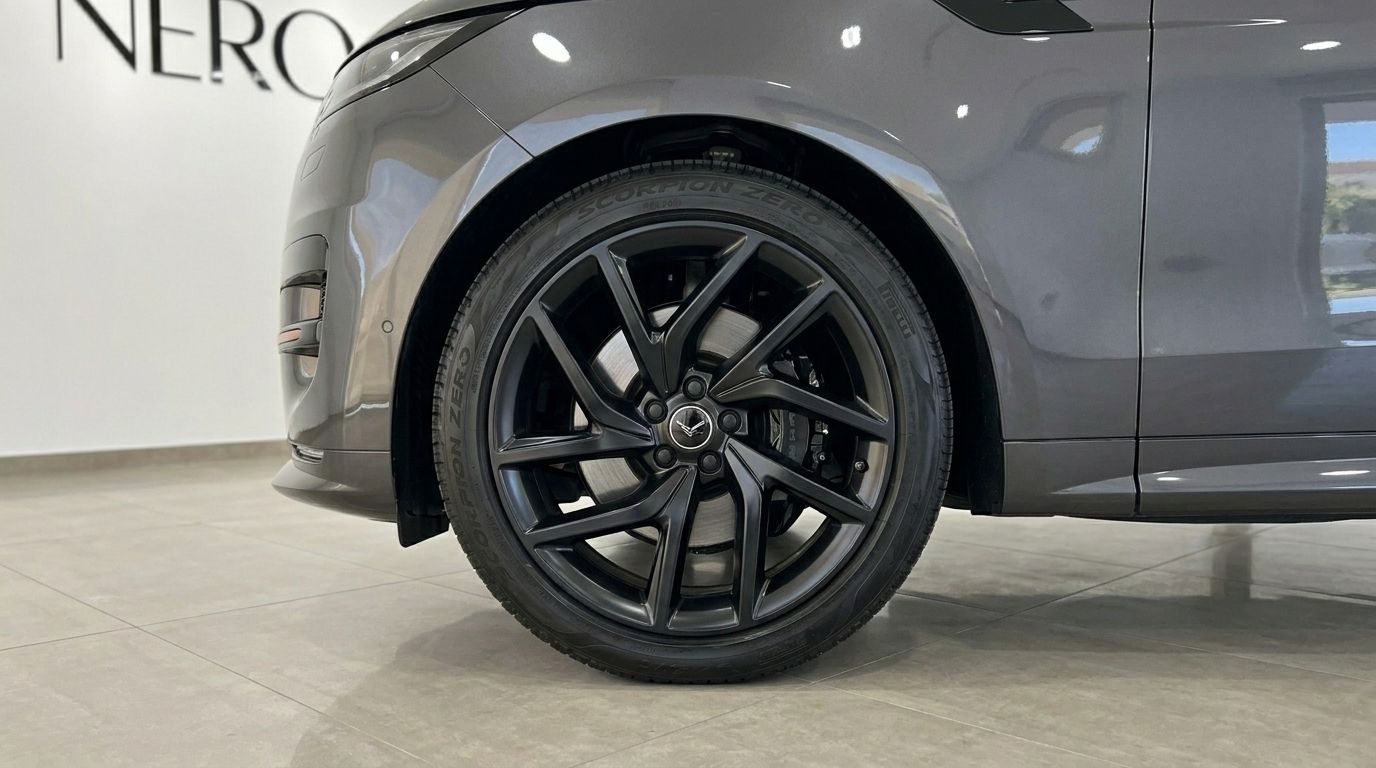 El Range Rover Sport 2023 en gris metálico oscuro brillante destaca su elegante rueda delantera negra de radios múltiples y guardabarros en Madrid.