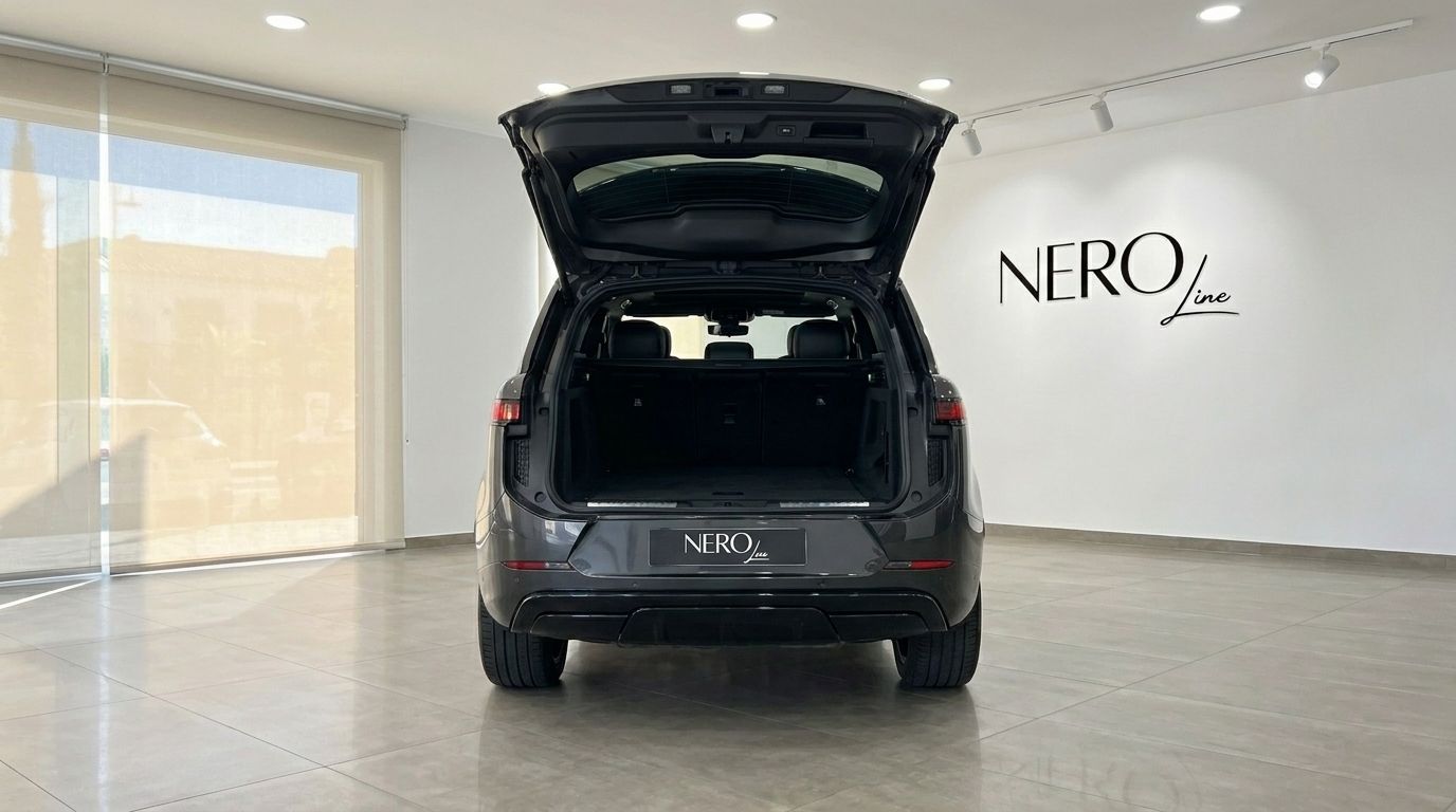 El Range Rover Sport 2023 gris, visto desde la parte trasera con el maletero abierto, expuesto en un showroom en Madrid.