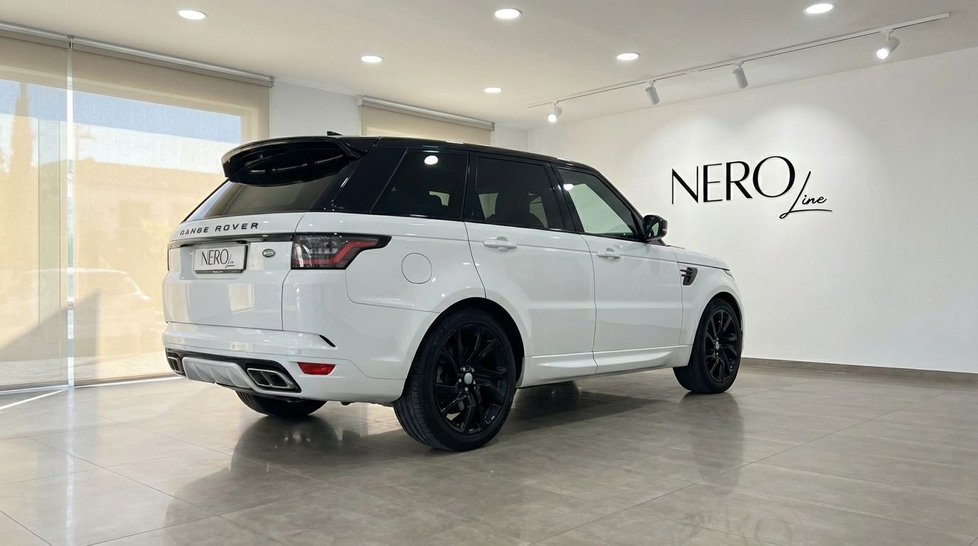 A white and black 2022 Range Rover Sport is parked in a showroom, viewed from the rear three-quarter angle in Barcelona.