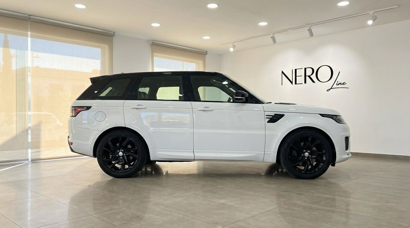 The white and black 2022 Range Rover Sport is showcased in a side profile view within a showroom in Barcelona.