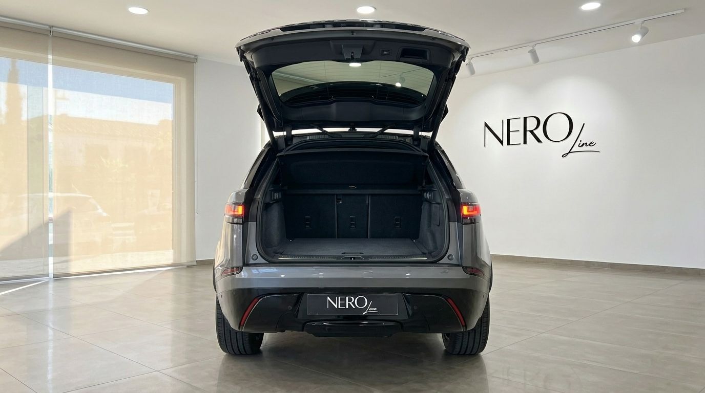 The image shows the rear view of a metallic Carpathian Grey 2024 Range Rover Velar Autobiography with its trunk open, parked in a showroom in Marbella.