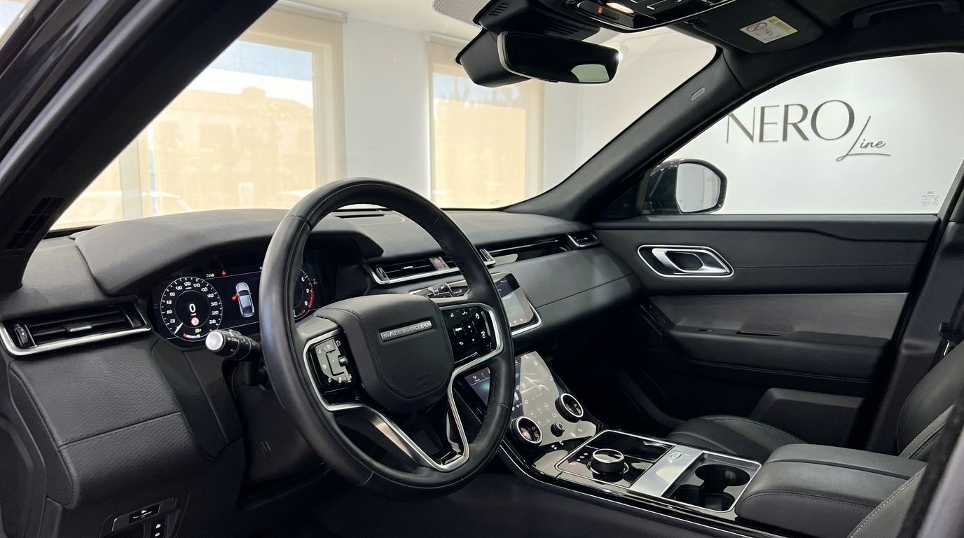The luxurious interior of the Range Rover Velar in Alicante, featuring the steering wheel, digital dashboard, and infotainment system.