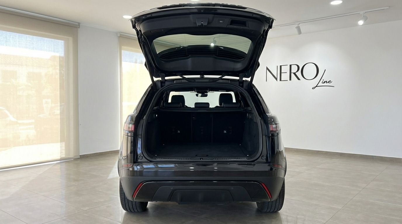 The black Range Rover Velar is shown from the rear with its trunk open, highlighting the spacious cargo area in Alicante.