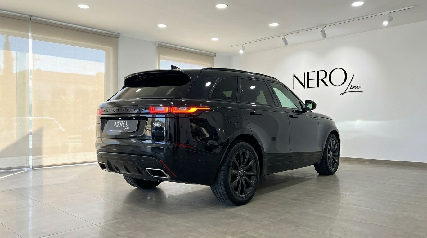 The metallic black 2022 Range Rover Velar is shown from a rear three-quarter angle in a showroom in Alicante.