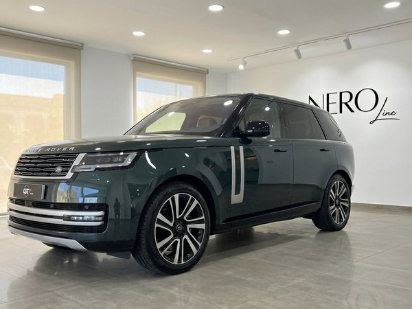 Range Rover Vogue — SUV de lujo en Madrid El Range Rover Vogue 2022 verde oscuro se exhibe desde un ángulo frontal tres cuartos en una moderna sala de exposición en Madrid.