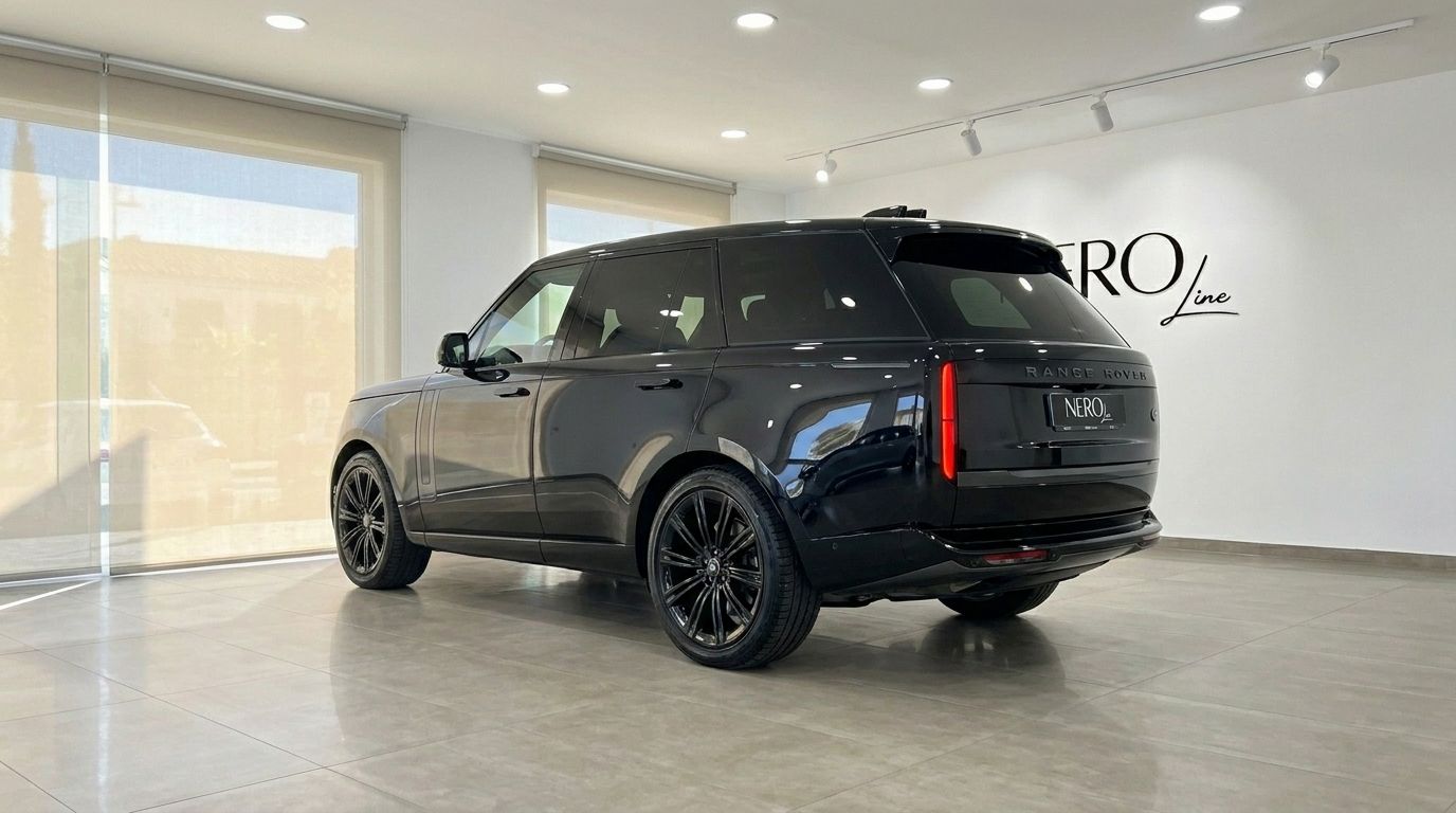 El Range Rover Vogue Autobiography negro de 2023 se exhibe desde una vista trasera tres cuartos en un luminoso concesionario de Madrid.