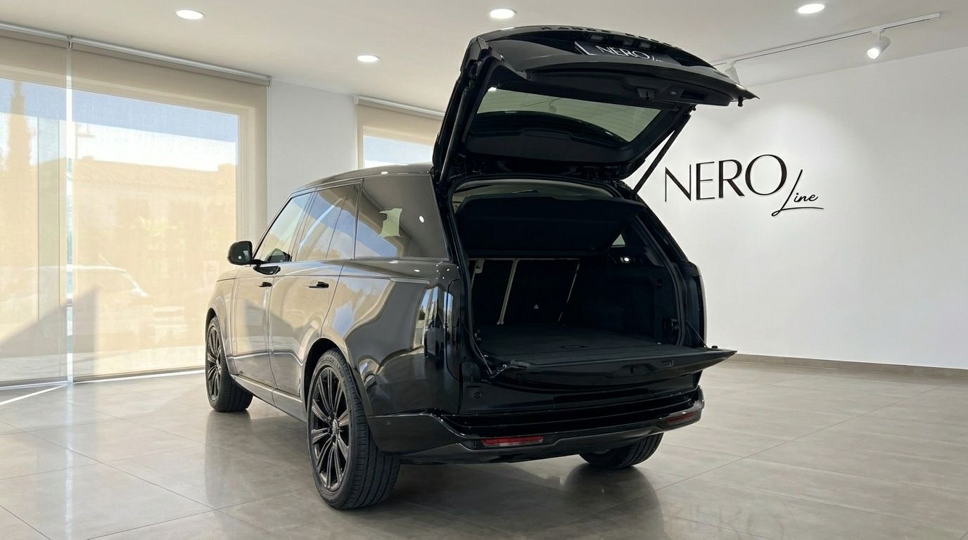 The black 2026 Range Rover Vogue HSE LWB is shown from the rear with its trunk open, parked in a showroom in Marbella.