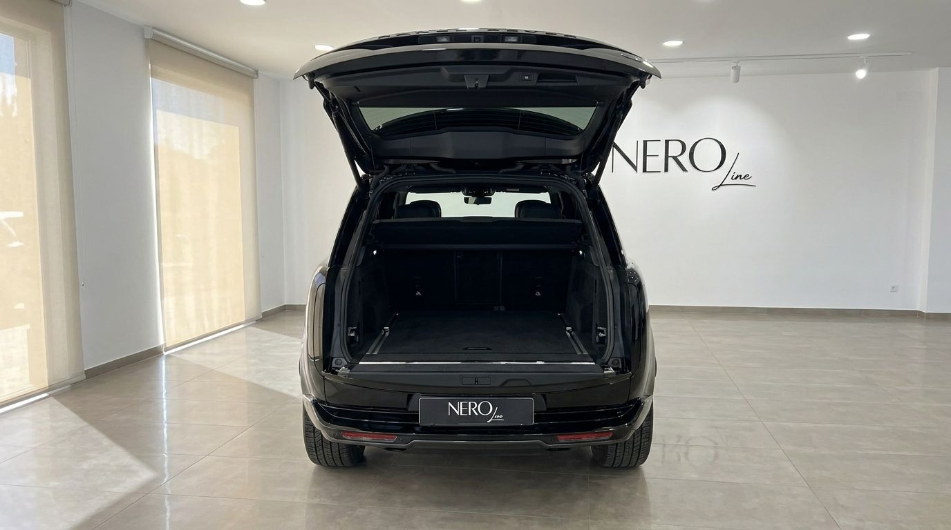 The rear view of the 2025 Range Rover Vogue LWB Autobiography in gloss Santorini Black with its spacious boot open, parked in Marbella.