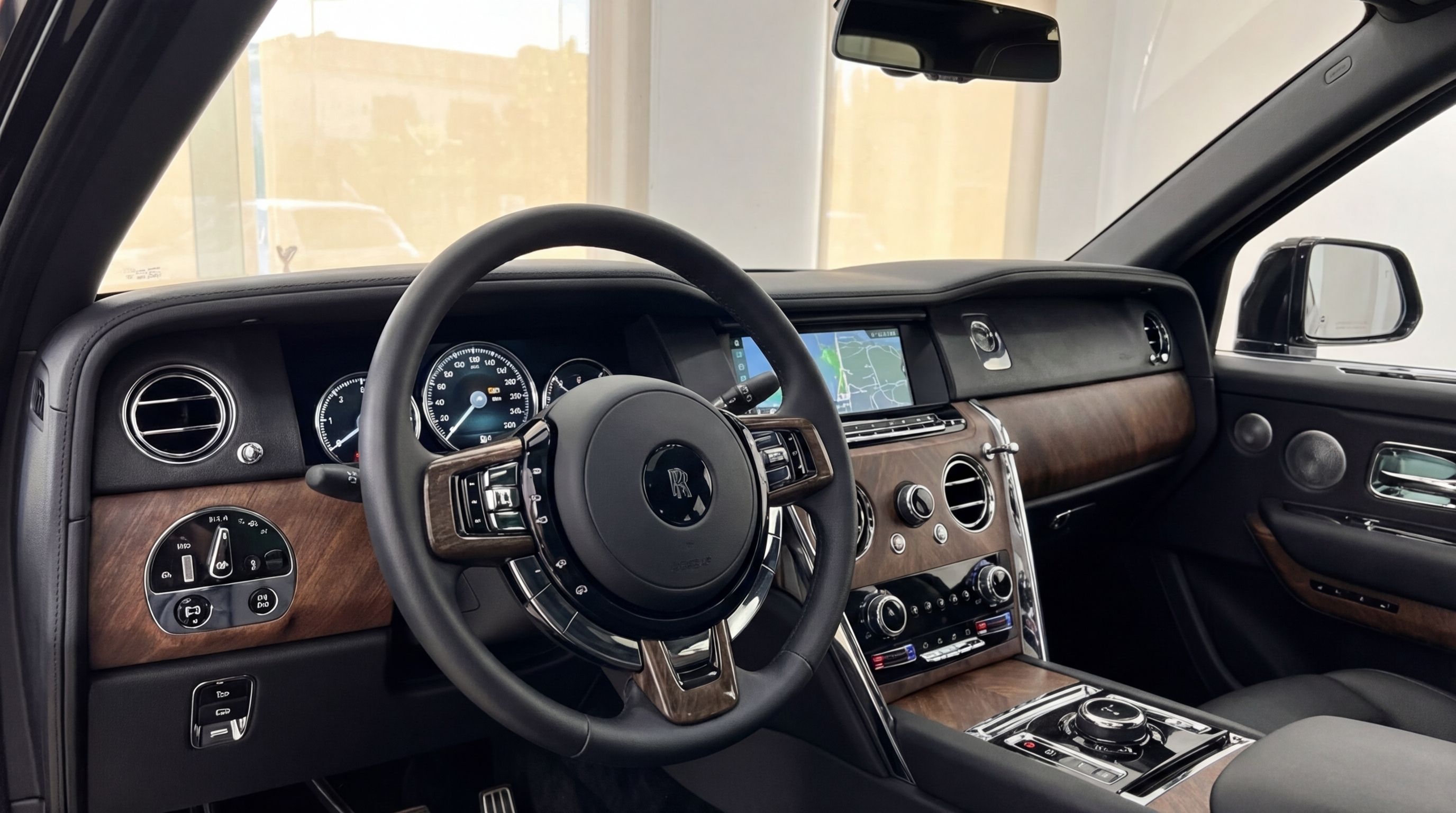 Rolls-Royce Cullinan interior in Ibiza, showcasing the luxurious cockpit with steering wheel, digital dashboard, and elegant wood trim.