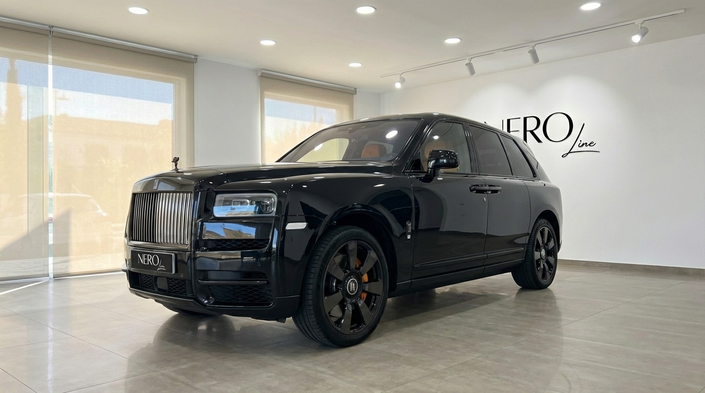 Rolls-Royce Cullinan — Vista frontal tres cuartos Un SUV Rolls-Royce Cullinan 2025 negro brillante se exhibe desde una vista frontal tres cuartos en un concesionario en Madrid.