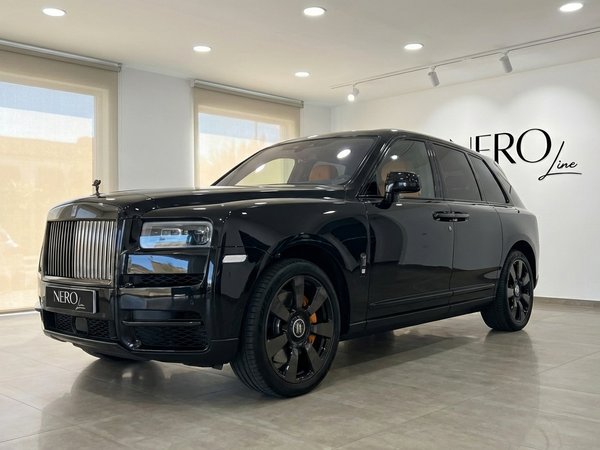 Rolls-Royce Cullinan — Vista frontal tres cuartos Un SUV Rolls-Royce Cullinan 2025 negro brillante se exhibe desde una vista frontal tres cuartos en un concesionario en Madrid.